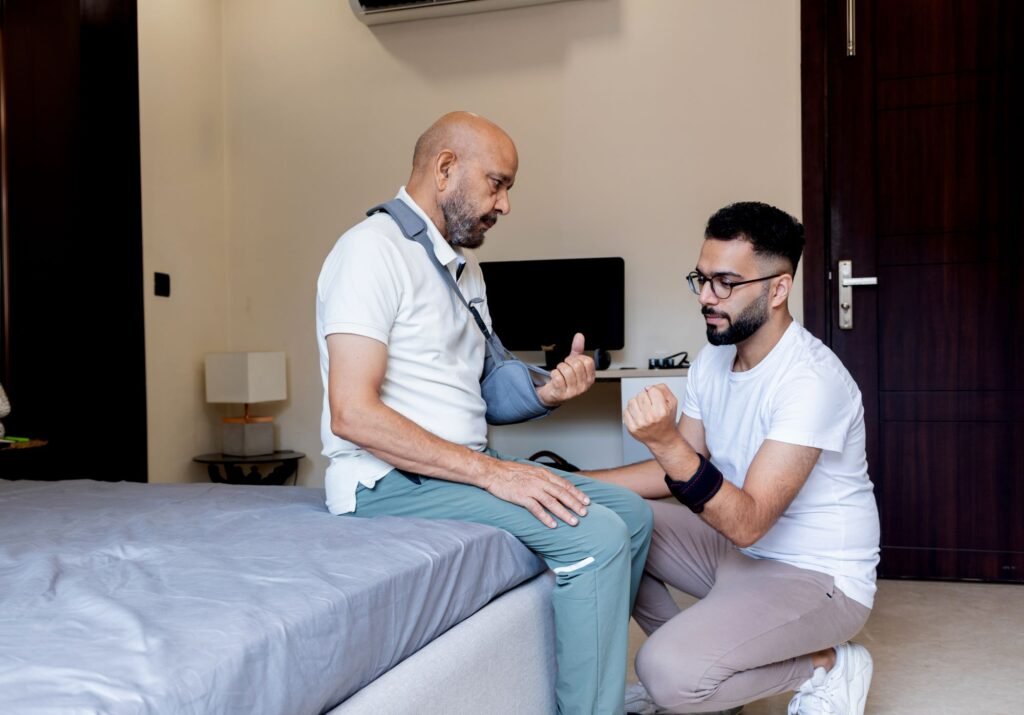 Post-Surgery Care - Nurse with man whose arm is in a sling, sitting on a bed